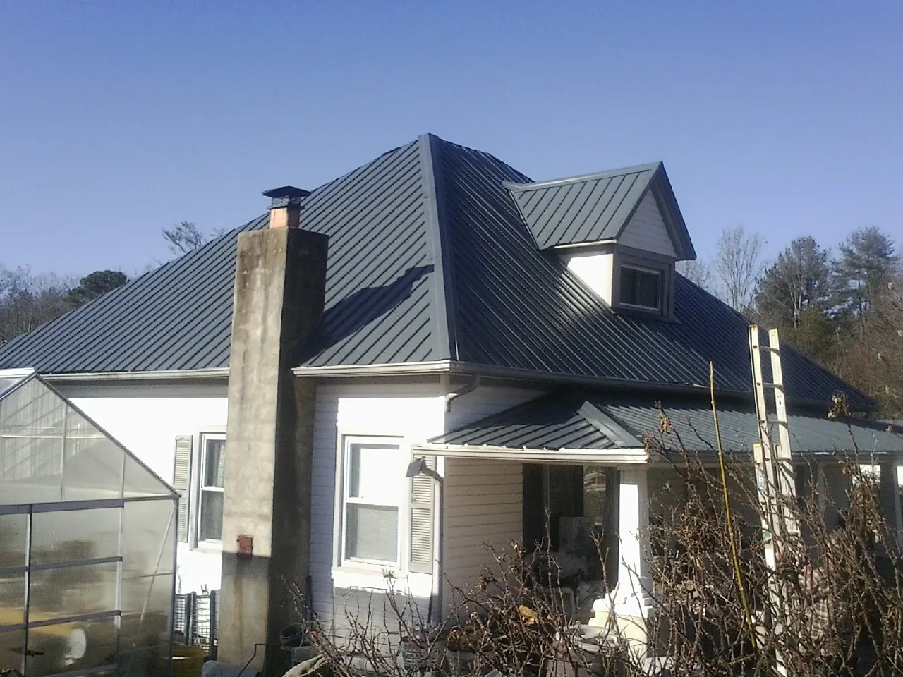 Dark blue standing seam metal roof on a white farmhouse with dormer — Slate & Tile Roof Repair by Roofing Brothers in Twinsburg
