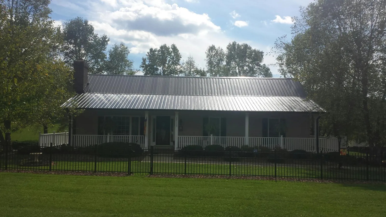 Gray metal roof on a brick ranch with a full width front porch — Gutter Guard Installation work by our crew in Twinsburg