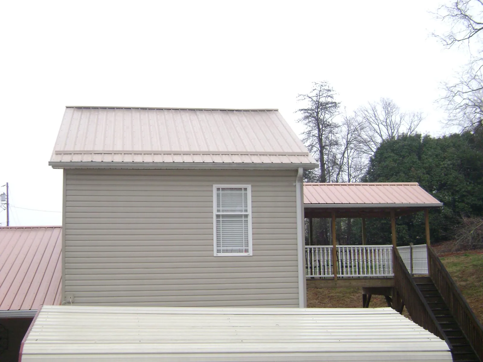 Tan metal roofs on a two story addition and attached porch, from a Roof Replacement job in Twinsburg