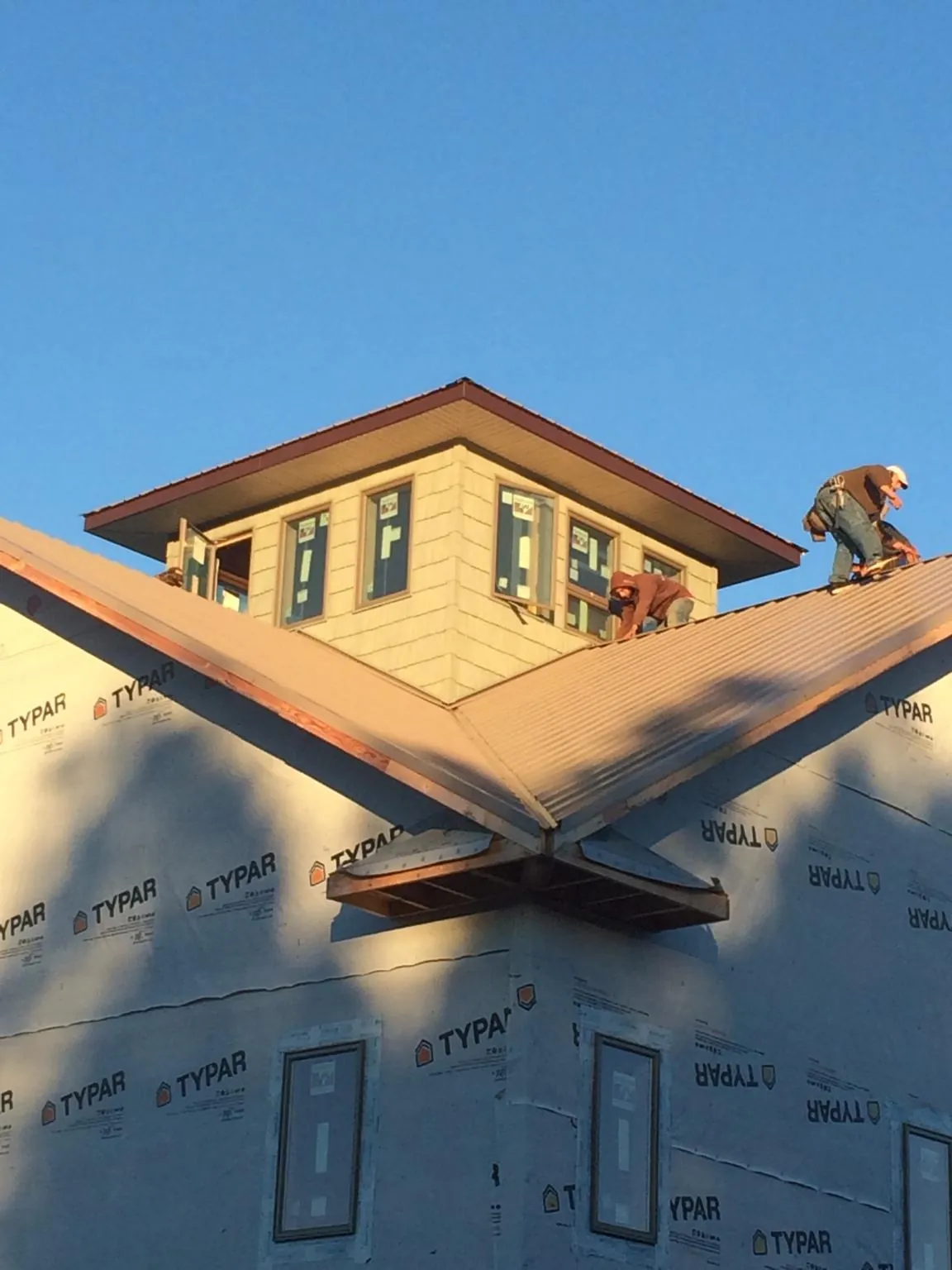 Roofers working around a rooftop cupola on a new metal roof at sunset — Roof Waterproofing in Twinsburg by Roofing Brothers